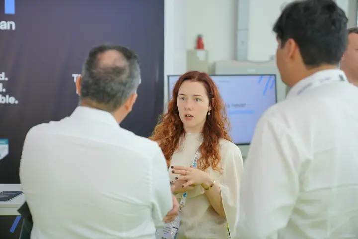MetisJean at AI Everything Abu Dhabi: a member of the team answering questions from two visitors